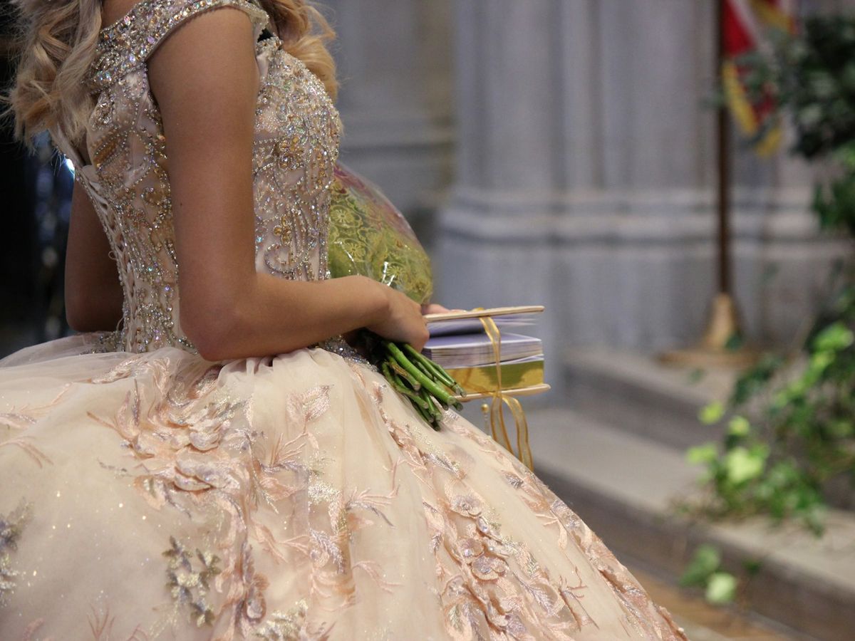 Quinceañera con vestido bordado y ramo en las manos